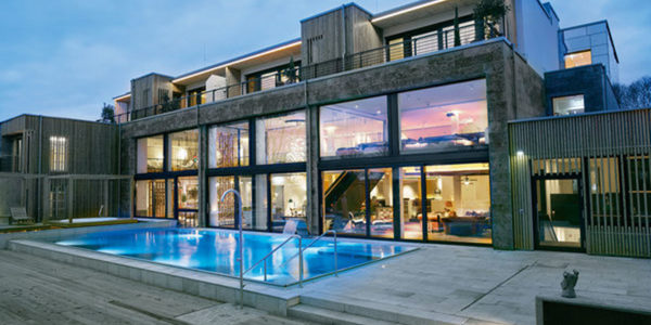 Pool und Außenansicht des Hotels Voshoevel bei Dämmerung.