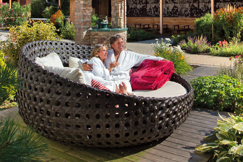 Ein Mann und eine Frau sitzen auf einem runden Stuhl im Freien.