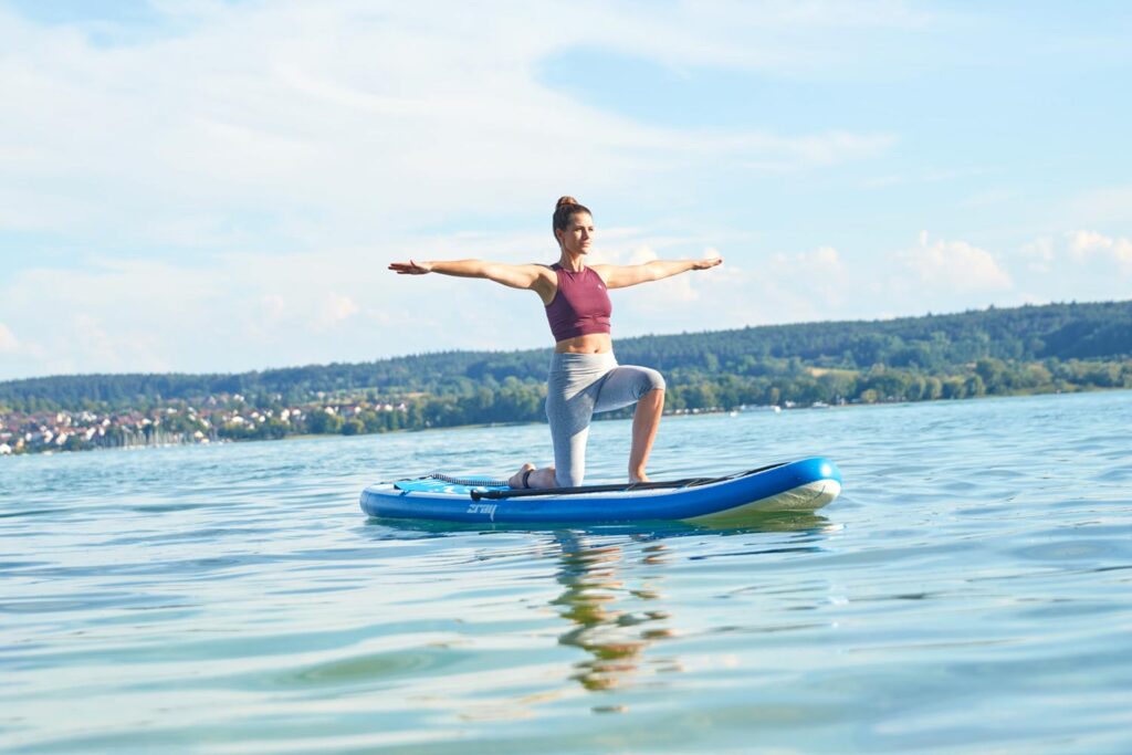 Junge Frau Macht Yoga auf einem SUP Board am Bodensee
