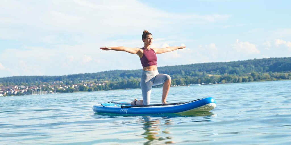 Junge Frau Macht Yoga auf einem SUP Board am Bodensee