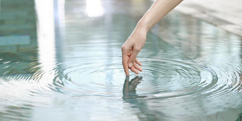 Finger taucht ins Wasser sodass Waserkreise entstehen